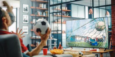 Männer schauen auf dem Sofa vor dem Fernseher Fußball